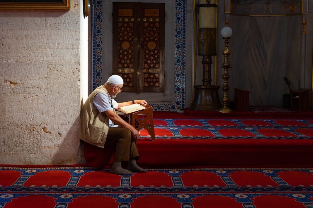 Un homme lit le Coran dans une mosquée